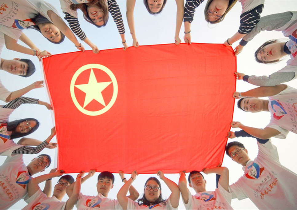 College students in Zhenjiang, Jiangsu province, hold a flag of the Communist Youth League to celebrate the upcoming 100th anniversary of the May Fourth Movement, April 15, 2019 (Photo: China Daily, 2019).